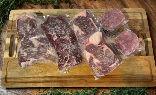 flank steak, tri tip, rib eyes and hamburger patties on a cutting board